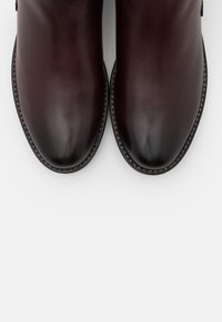 Bottines en cuir marron avec une finition lisse, bouts arrondis, coutures contrastées et fermeture à glissière sur le côté.