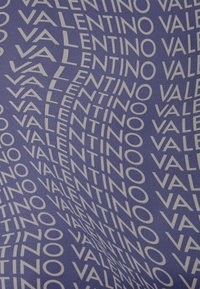 Textil púrpura con un logo blanco "VALENTINO" repetitivo en diversas orientaciones, creando un efecto visual dinámico. Textura suave.