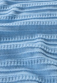 Tissu tricoté bleu clair avec des rayures horizontales, présentant différentes textures et motifs de points lisses et côtelés.