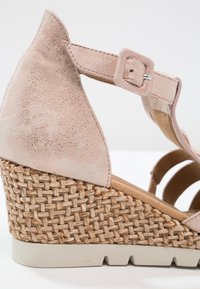Sandale compensée avec plateforme en paille tressée, bride de cheville en daim beige et fermeture à boucle réglable, vue rapprochée de profil.