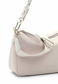 Jasnobeżowa skórzana torba na ramię z plecionym paskiem, srebrnym suwakiem, regulowaną tkaninową klamrą oraz metalowym zapięciem, z logo "SURI FREY" na boku.