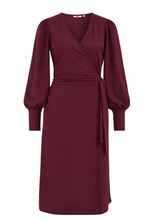 Bordeaux wikkeljurk van zachte stof, met een diepe V-halslijn, pofmouwen en een strikceintuur op de taille. Lengte tot halverwege het kuit.