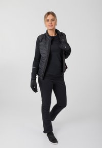 Schwarze isolierte Weste, schwarzes Langarmshirt, schwarze Hose und Handschuhe. Glatte Textur, funktionales Design, geeignet für Aktivitäten im Freien.