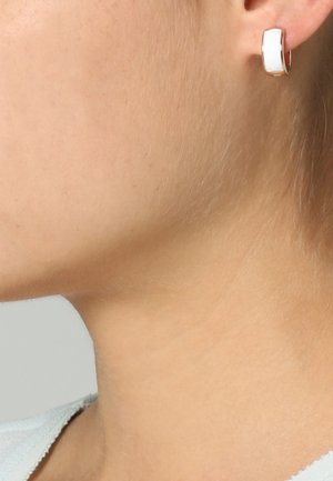 Boucles d'oreilles en or blanc et or rose, présentant un design courbé avec une surface lisse et une finition polie. Forme compacte, adaptée au port quotidien.