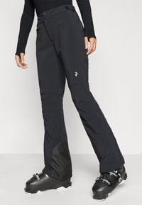 Svarta skidbyxor med en mjuk, strukturerad yta. Funkar inkluderar två knappar, sidofickor och förstärkta svarta detaljer vid nederdelen av benen.