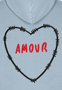 Ljust blå hoodie med ett hjärtmotiv som är detaljerat med svart søm, med ordet "AMOUR" broderat i rött i mitten.
