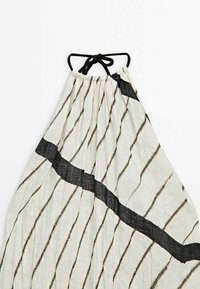 Lätt, rynkad klänning i krämfärgad, med svarta snedställda ränder och en knytning i nacken. Draperad, avslappnad silhuett.