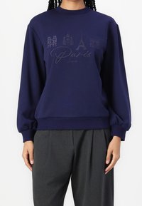 Sweat-shirt marine à manches longues, avec des monuments de Paris et un design en écriture dans des tons plus clairs ; fabriqué en tissu doux en mélange de coton.