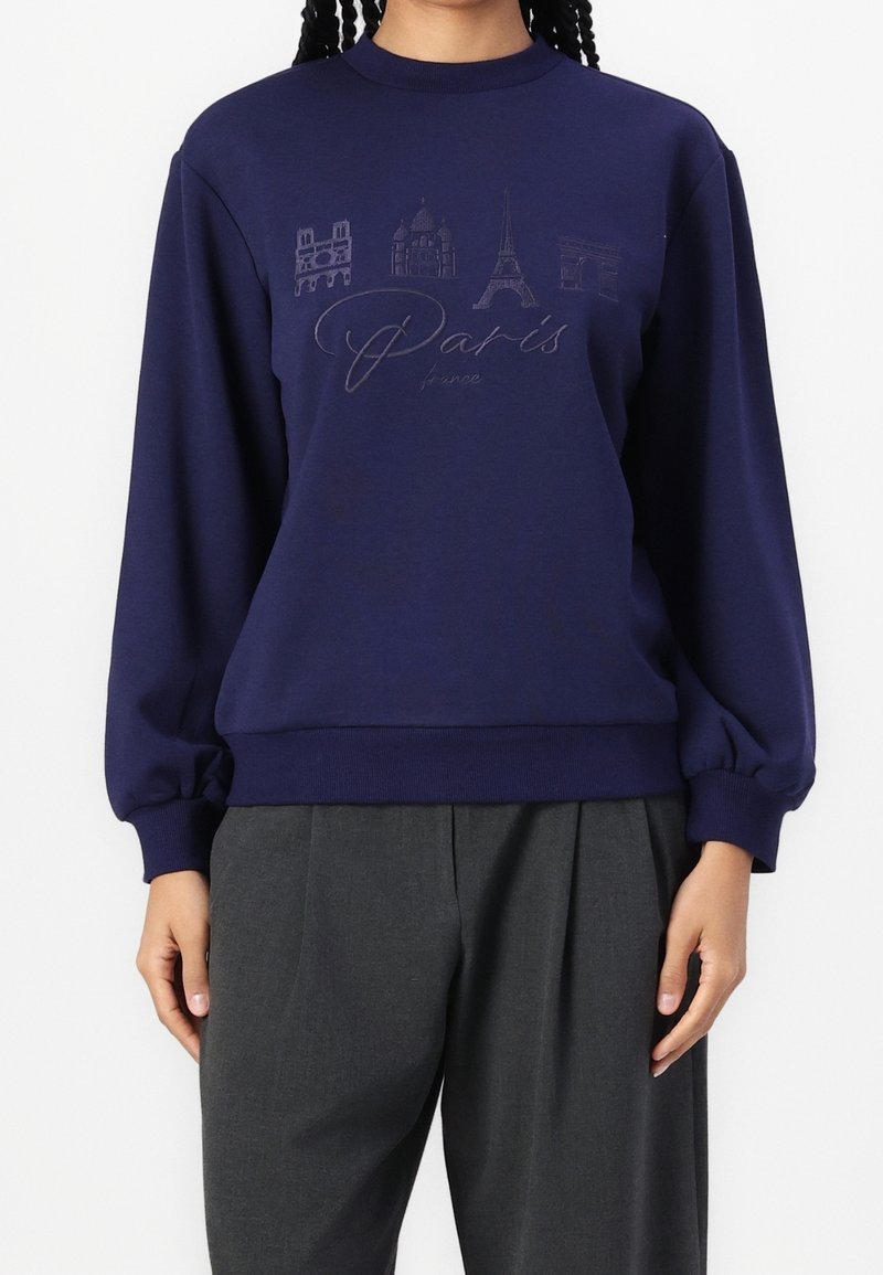 Sweat-shirt marine à manches longues, avec des monuments de Paris et un design en écriture dans des tons plus clairs ; fabriqué en tissu doux en mélange de coton.