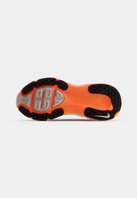 Suela de zapato con banda de rodadura de goma negra, entresuela naranja y acentos grises. Presenta un agarre con patrón y secciones moldeadas para tracción.