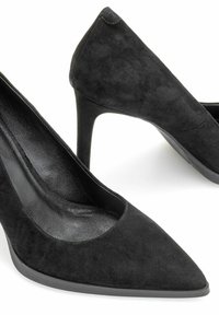 Czarne zamszowe szpilki z szpiczastym noskiem, obcasem w kształcie stiletto oraz zakrzywionym wykończeniem na otwarciu. Teksturowana powierzchnia i gładkie wykończenie wewnętrzne.