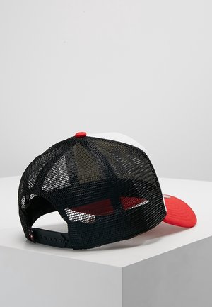 Casquette trucker en mesh noir avec une visière rouge incurvée et un bouton supérieur, fermeture snapback réglable, posée sur une surface blanche en angle.