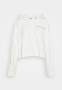 Skuren vit hoodie tillverkad av mjukt tyg med dragsko i huvan. Den har broderad text framtill och långa ärmar.