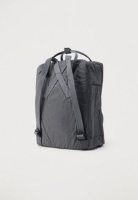 Γκρι υφασμάτινο σακίδιο με ρυθμιζόμενους ιμάντες, τετράγωνο σχήμα και κορυφαία λαβή. Διαθέτει λεία υφή και μινιμαλιστικό σχεδιασμό.