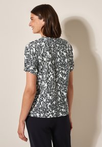 Korte mouw top met een textuur van een zwart-wit abstract patroon, ronde halslijn en zachte stof. Geschikt voor casual wear.