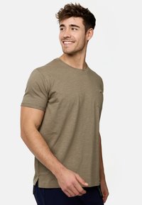 Olivgrünes T-Shirt aus weichem, strukturiertem Stoff mit kurzen Ärmeln, einem Rundhalsausschnitt und einer Brusttasche mit einem Knopfdetail auf der linken Seite.