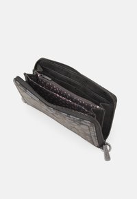 Czarny portfel o teksturowanej powierzchni, z zamkiem błyskawicznym, wieloma przegródkami oraz różową podszewką w kropki. Posiada metalową blaszkę z logo i miejsca na karty.