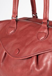 Red leather handbag with a smooth texture, featuring two top handles, a flap closure, and a front snap button detail.