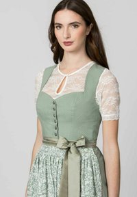 Green dirndl dress with a polka dot bodice, lace sleeves, decorative buttons, and a patterned skirt, finished with a satin bow at the waist.