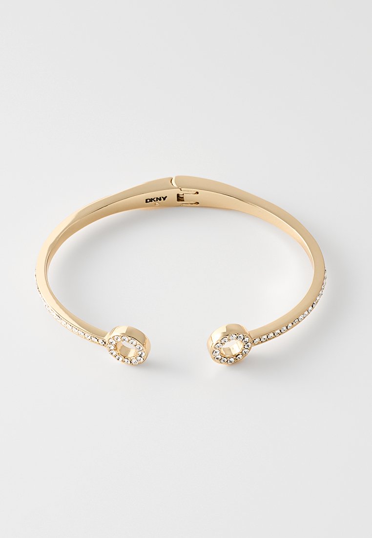 Armband aus goldfarbenem Metall mit zwei runden Enden, verziert mit kleinen, klaren Strasssteinen entlang des Bandes und der Kanten.