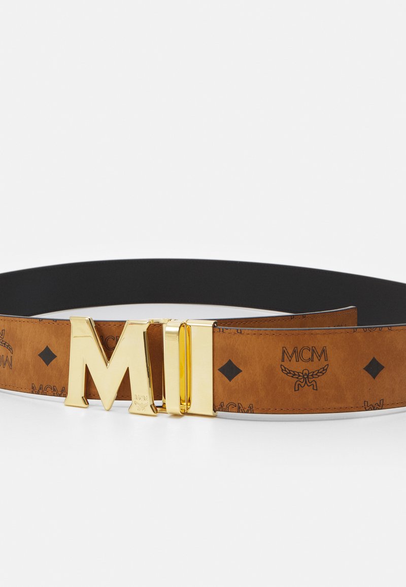 Brūns ādas jostas ir zelta tonu dubultā "M" sprādze, ar iegravētām MCM logo un dimanta rakstiem pa jostas siksnu. Melna iekšējā oderējuma.