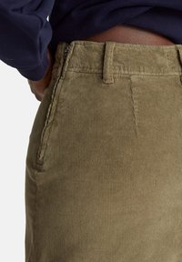 Kordové kalhoty v olivově zelené barvě, s měkkou texturou, bočními kapsami a zipovým zapínáním v pase.