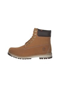 Botas de tobillo de cuero marrón con un acabado liso; herrajes dorados, collar acolchado en marrón oscuro y una suela robusta de color blanco y marrón.