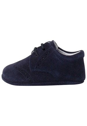 Chaussure bébé en daim bleu foncé avec lacets à l'avant, perforations style brogue et semelle souple, vue de profil sur fond blanc.