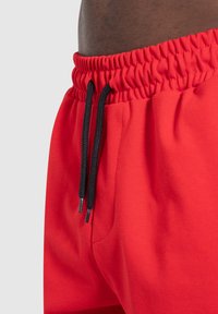 Rode sportieve shorts met een elastische tailleband, zwarte trekkoorden en zijzakken. Glad textuur en casual pasvorm, ontworpen voor comfort.