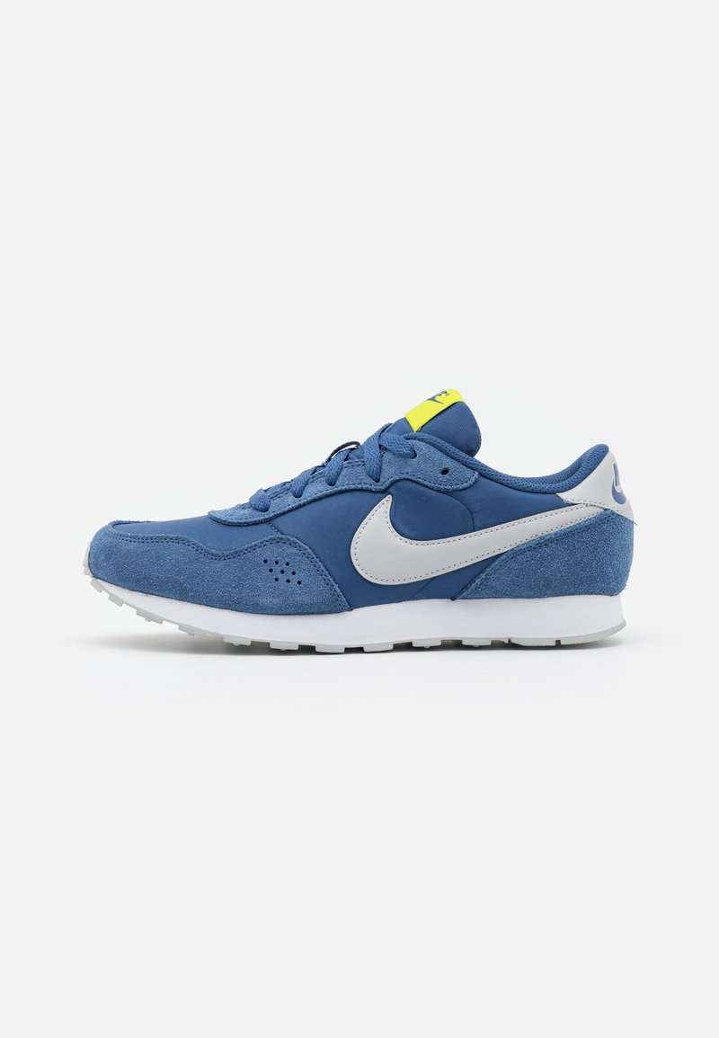 Baskets Nike bleues et blanches avec panneaux en daim et en mesh, semelle blanche, et étiquette jaune néon sur la languette, vues de profil.