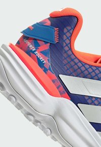 Sport shoes featuring a textured blue upper with orange accents, silver details, and a patterned heel. White rubber sole with traction lugs.