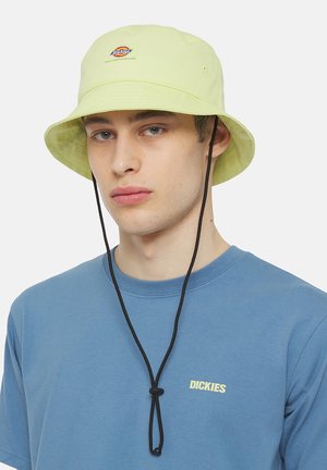 Light green bucket hat with a flat brim, adjustable black drawstring, and a small circular logo patch on the front.