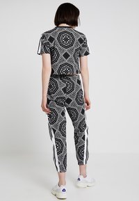 Svart och vit mönstrad träningsset som består av en croppad topp och tapered byxor, med kontrasterande sidostråkar och en mjuk textur.