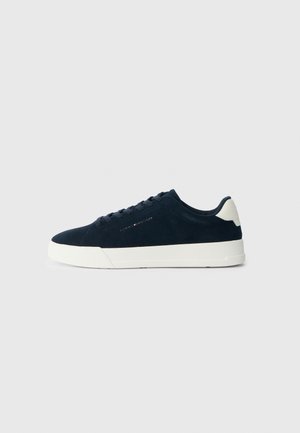 Navy suede sneaker with white rubber sole, rounded toe, and contrasting heel tab; features tonal laces and a logo detail on the side.