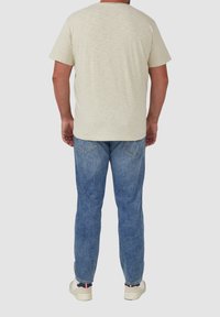 Helles beige T-Shirt mit kurzen Ärmeln und blauen geraden Jeans, im klassischen Schnitt, mit einfacher Textur und minimalistischen Design.