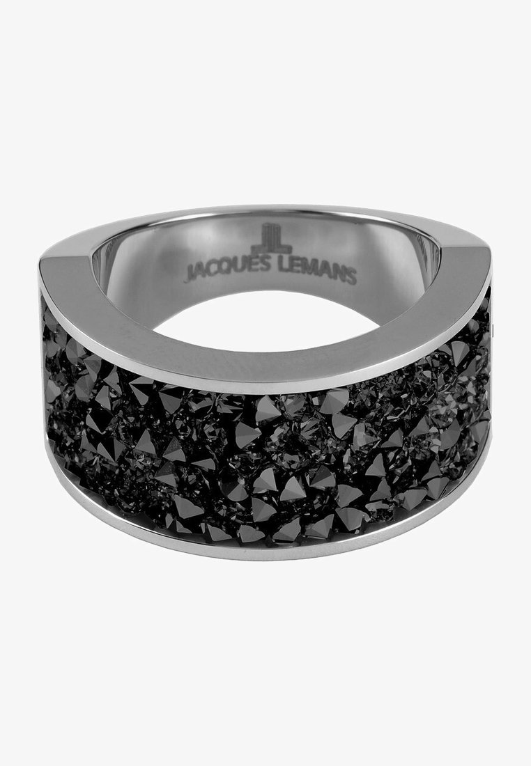 Schwarzer Ring mit breitem Band, das eine strukturierte, klobige Oberfläche aus schwarzen Kristallen aufweist, eingesetzt in einem polierten Metall in Silberfarbe. Markenname innen sichtbar.