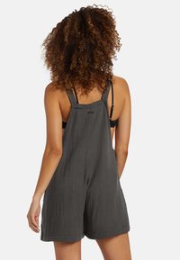 Tutina in tessuto grigio scuro intrecciato con spalline regolabili, vestibilità ampia e superficie testurizzata. Visuale posteriore che mostra il design complessivo.