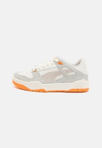 Zapatillas con una combinación de cuero blanco y gamuza gris. Presentan acentos naranjas en la suela y ojales. Parte superior texturizada y cordones planos.