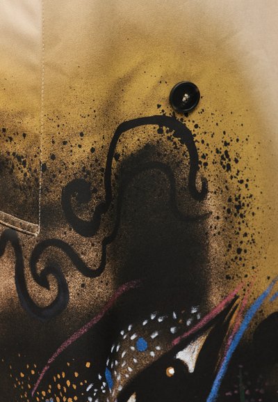 Ύφασμα ταμπά με μαύρο κουμπί, διακοσμημένο με μαύρα σπειροειδή σχέδια από σπρέι και κηλίδες σε αποχρώσεις μπλε, λευκού και πορτοκαλί κοντά στην κάτω άκρη.