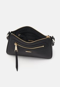 Bolsa DKNY preta com uma textura lisa, hardware dourado, múltiplos compartimentos com fecho éclair e um design elegante e angular. Interior com slots para cartões.