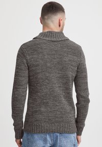 Szary, dziany sweter z szerokim kołnierzem, ribbed mankietami i dołem. Posiada teksturowany wzór w różnych odcieniach, co dodaje wizualnego zainteresowania.