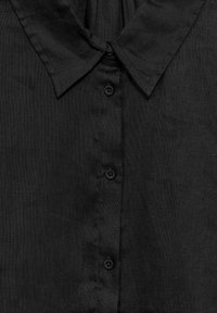 Chemise en lin noire présentant un col classique, une fermeture boutonnée à l'avant et une finition en tissu texturé. Apparence globale lisse avec des détails subtils.