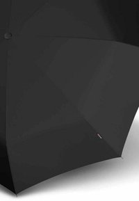 Paraguas compacto negro con acabado liso mate, con un botón circular y una etiqueta de marca sutil en el borde.