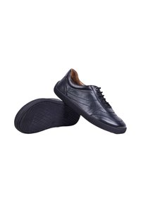 Baskets décontractées en cuir noir avec lacets, une chaussure montrant le dessus et l'autre la semelle texturée, isolées sur fond blanc.