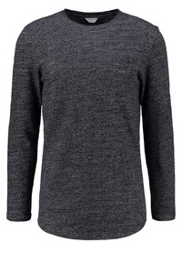 Camisa de manga larga en gris oscuro, con una tela de punto texturizada y un pequeño bolsillo en el pecho. Dobladillo redondeado y cuello estilo crew.