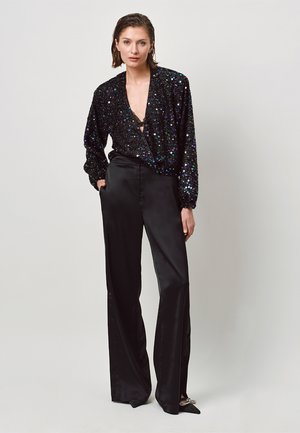 Zwarte paillettenblouse met een diepe V-hals en poufsleeven, gecombineerd met zwarte satijnen broek met hoge taille en een gladde afwerking.