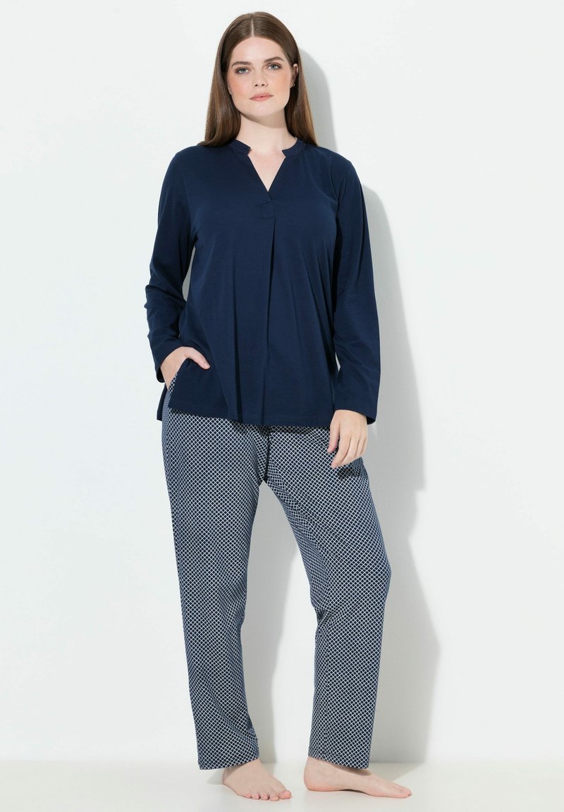 Tienda de manga larga azul marino con escote en V y detalle de pliegue, combinada con pantalones estampados en un diseño geométrico azul y blanco. Tela suave, corte relajado.