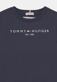 Námořnická modrá tričko z organické bavlny s kulatým výstřihem, s bílým textem "Tommy Hilfiger", logem značky a "EST. 1985" na přední straně.