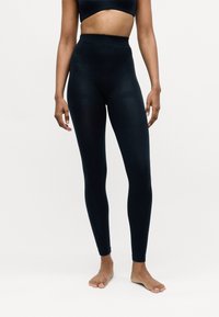 Hoch taillierte schwarze Leggings aus einem dehnbaren Material, mit einer glatten Textur und ohne sichtbare Nähte, entworfen für eine figurbetonte Passform.