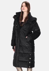 Czarna, puchowa kurtka o błyszczącym wykończeniu, pikowanym wzorze, wysokim kołnierzu i ozdobnych guzikach. Posiada długie rękawy oraz boczne kieszenie.